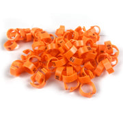 Orange plastic numbered bird leg bands scattered in a pile, showing various numbers like 75, 84, 98