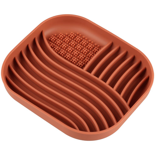 Orange silicone slow feeder bowl with ridged design and textured center section on white background