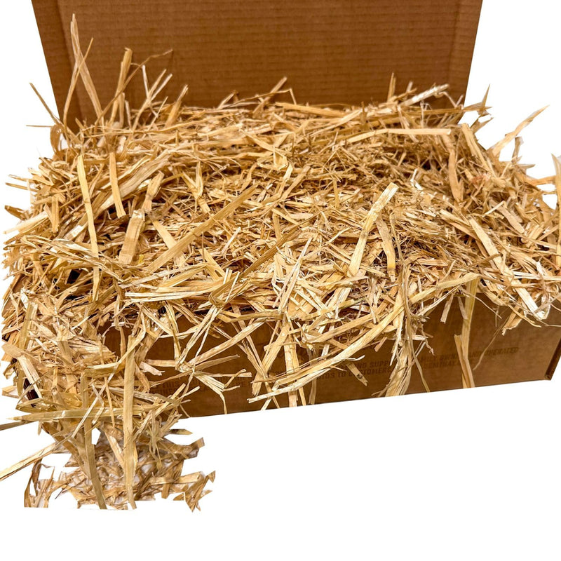 Golden straw bedding overflowing from brown cardboard box against white background
