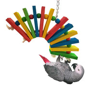 African Grey parrot hanging upside down from colorful wooden block chew toy with beads