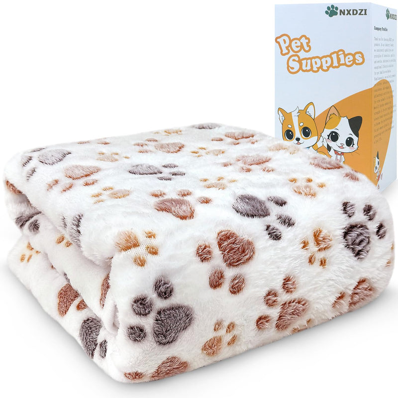 White coral velvet dog blanket with brown and gray paw print pattern next to product box