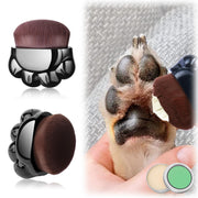 Black paw-shaped makeup brush applicator being used on wet dog's paw pads with balm containers