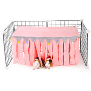 Pink guinea pig hideout with fabric strips attached to wire cage, two guinea pigs underneath
