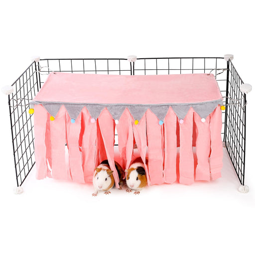 Pink guinea pig hideout with fabric strips attached to wire cage, two guinea pigs underneath