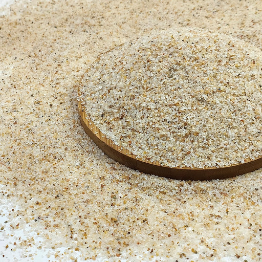 Close-up of fine beige aquarium sand substrate with wooden measuring tool showing texture detail