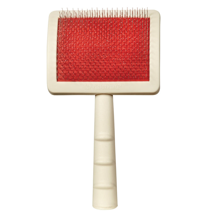 Large slicker brush with red bristle pad and cream colored handle on white background