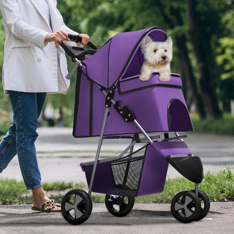 White West Highland Terrier sitting in purple pet stroller being pushed by woman in park