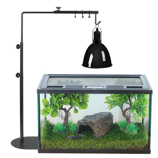 Black adjustable heat lamp stand positioned over glass terrarium with artificial plants and rocks