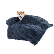 Shiba Inu dog lying comfortably on dark gray plush couch-style bed with matching fuzzy blanket