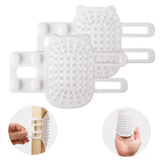 White bear-shaped silicone cat brush with straps shown attached to crib rail and in hand