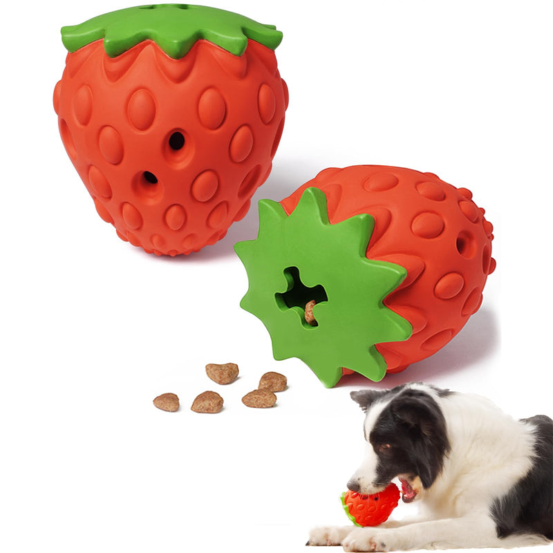 Red strawberry-shaped dog puzzle toys with green leafy tops, kibble scattered nearby, puppy playing