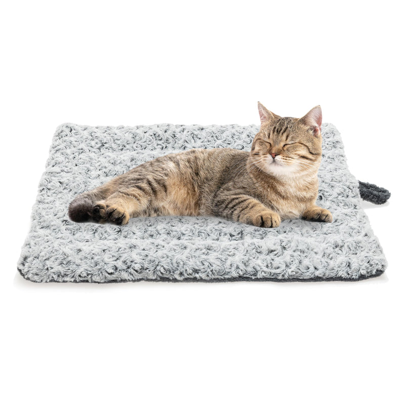 Brown tabby cat lying contentedly on gray fuzzy self-warming pet bed mat against white background