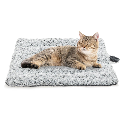 Brown tabby cat lying contentedly on gray fuzzy self-warming pet bed mat against white background