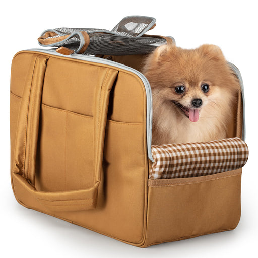 Small orange Pomeranian dog with tongue out sitting inside tan travel carrier bag with mesh top