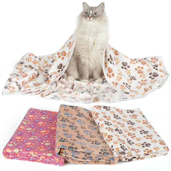 Three folded fleece pet blankets with paw print patterns in pink, brown, and white colors