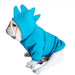 French bulldog wearing turquoise dinosaur hoodie with spikes, sitting and looking to the side