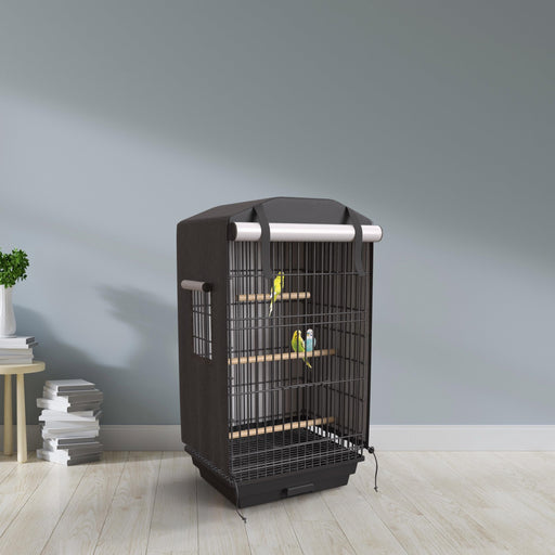 Black bird cage cover on tall cage with colorful parakeets inside, styled in modern room