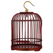 Red wooden bird cage with vertical slats and brass hanging hook on white background