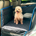 Cream poodle sitting in waterproof car seat extender with blue trim in vehicle backseat
