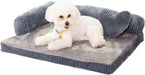 White Bichon Frise dog lying on gray corduroy L-shaped orthopedic bed with raised sides