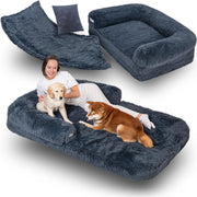 Woman lying on large dark gray fuzzy dog bed with golden retriever puppy and shiba inu