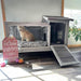 Large wooden rabbit hutch with wire enclosure, dark shelter area, ramp, and Easter sign nearby