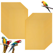Golden yellow bird cage liner papers displayed in two neat stacks with colorful parrots